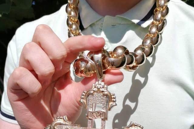 Hansons Auctioneers' trainee valuer Daniel Armstrong wears the chain. See SWNS story SWMRcross; The biggest gold crucifix and chain in the UK which weighs 1.5kg is set to fetch £30k at auction - with bling-loving boxers Tyson Fury and Anthony Joshua being offered first dibs.