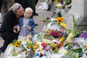 A woman kisses a small child as they look at the flowers laid outside Buckingham Palace, London, following the death of Queen Elizabeth II on Thursday. Picture date: Friday September 9, 2022.