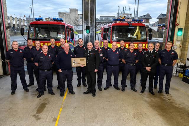 Firefighter McMullen  is presented with an axe by Chief Fire Officer Justin Johnston and the crew at Colne Fire Station. Photo: Kelvin Stuttard