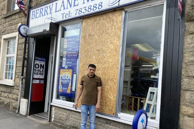 Mustak Chhadat pictured by  the smashed and boarded up  window at his shop Berry Lane News