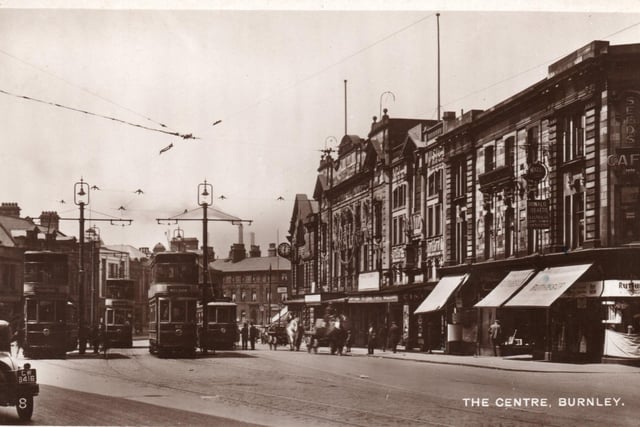 The Centre, Burnley, probably in the late 1920’s. To the right are the Palace and Grande Theatres. The building with the clock is the Tram Office and, in the foreground, right, is Seed’s Café, the forerunners of Oddie’s. Ruthies Ltd., and Brunton’s, the photographers can also be seen. There are four trams in the image, two single-deckers and two double-deckers