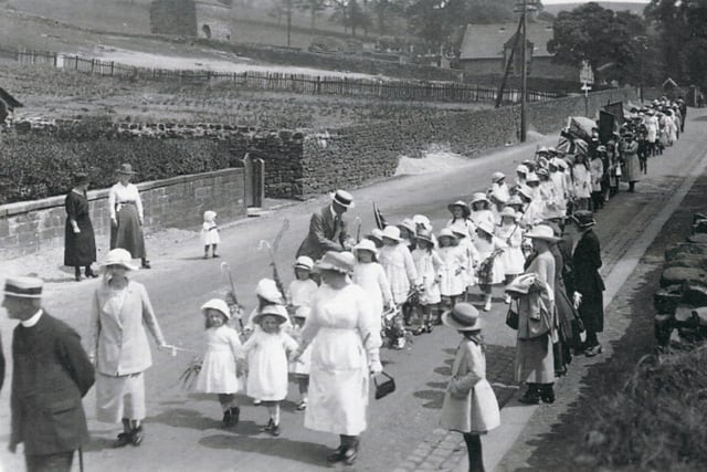 A Sunday School procession on the road between Holme-in-Cliviger and Walk Mill. The image must have been taken in about 1900. One of the volunteers is wearing a straw hat of about that time as are the Vicar and another gentleman, on the left. The school and the church gates can be seen in the background.