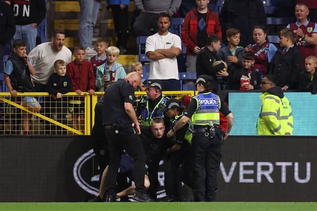 BURNLEY, ENGLAND - AUGUST 11: A spectator (whose face has been blurred) is arrested by the police after attempting to run on the pitch during the Premier League match between Burnley FC and Manchester City at Turf Moor on August 11, 2023 in Burnley, England. (Photo by Nathan Stirk/Getty Images)
