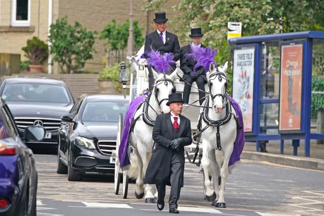 A horse drawn hearse adorned in purple arrives for the funeral. (Credit: PA/ Peter Byrne)