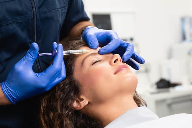 Close up of a beautician's hands injecting Botox in a female's forehead.