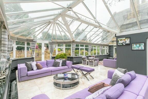 Large L-shaped living conservatory constructed of stonework with side windows and return pitched roof. Ceramic tiled flooring, two separate seating areas, built in corner bar fitment.