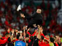 TOPSHOT - Morocco's coach #00 Walid Regragui is thrown into the air as Morocco players celebrate winning on penalty shoot-out the Qatar 2022 World Cup round of 16 football match between Morocco and Spain at the Education City Stadium in Al-Rayyan, west of Doha on December 6, 2022. (Photo by Odd ANDERSEN / AFP) (Photo by ODD ANDERSEN/AFP via Getty Images)