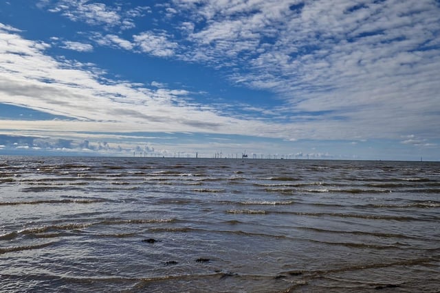 A windfarm and an oil rig in the distance out to sea at Crosby Beach