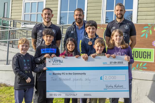 Burnley FC players Josh Brownhill (left) and Jay Rodriguez (right) presenting the cheque to Ben Bottomley (middle) from Burnley FC in the Community at Whitehough Outdoor Centre. Also in the picture are children from St Mary's CE Primary School, Rawtenstall.