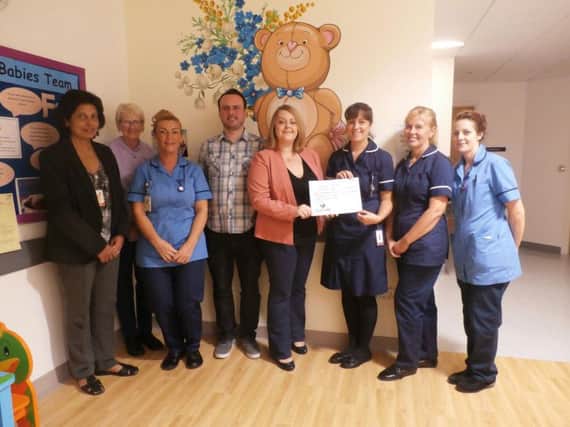 Neil Ibbotson and Louise Helsby (centre) present a cheque for 1,227 to Neonatal Specialist Practitioner Lisa Slater, surrounded by members of staff on the NICU ward.