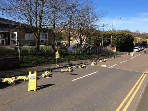 The startling image of pupils pictured lying on the zig-zag lines outside Wellfield Primary School was intended to drive home the message to par safely.