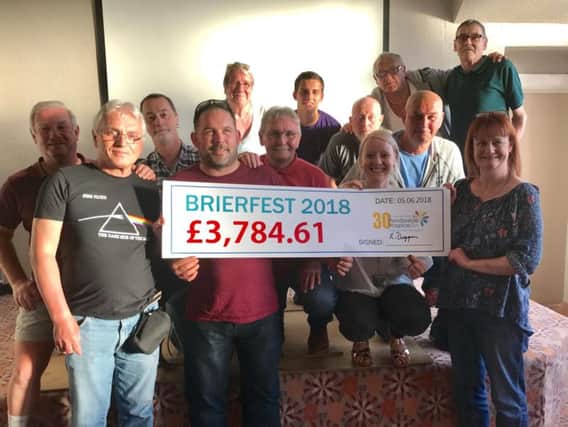 Pendleside Hospice fundraiser Leah Hutchinson from Pendleside receives the cheque at Brierfield Working Men's Club from Luke Hamilton, Phil Schofield and other club members.