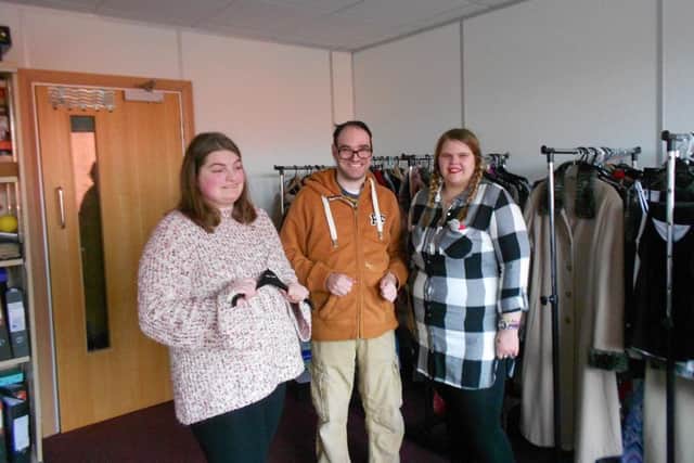 Three members of Team Rise prepare to model clothes donated to the group to sell on ebay to raise funds.