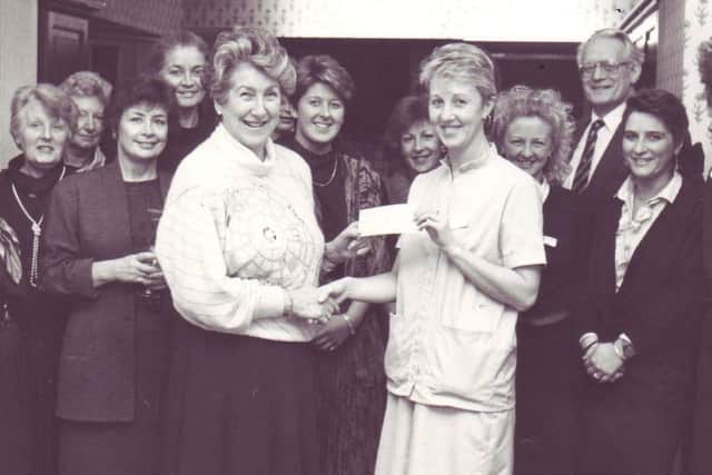 Maureen Cookson, front left, presenting a cheque to charity. Her daughter Hilary is on the right directly behind her and her husband Alan is second from the right. They are joined by members of staff.