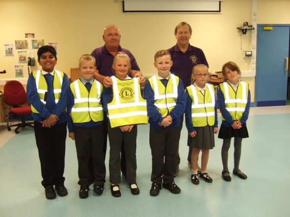 Burnley Lions Vice President Stephen Hunt and President Frank Seed present the hi-vis vests to some of the pupils at Padiham Primary School.