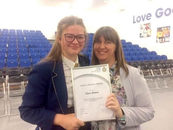 Alyssa Bristow with her mum Amanda and the award she received for saving her life