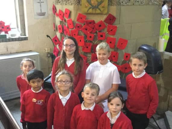 Some of the pupils from Earby Springfield Primary School pictured with the woven poppies they made on display.