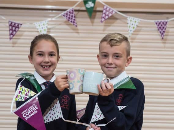 Max Carrington and Mia Smith say cheers at the Macmillan coffee morning at their school, St Augustine's RC Primary in Burnley.