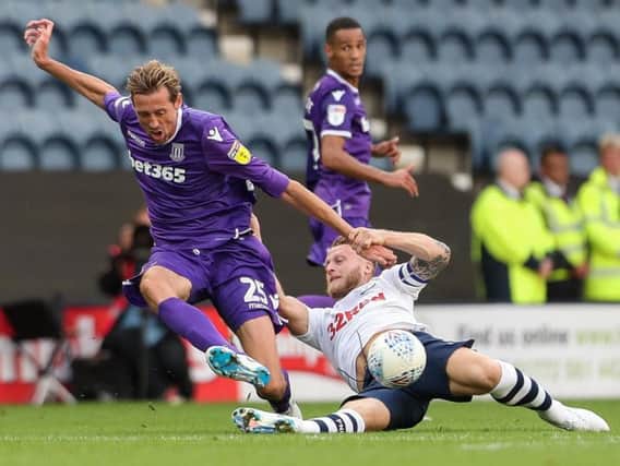 Preston North End's Tom Clarke tackles Stoke City's Peter Crouch