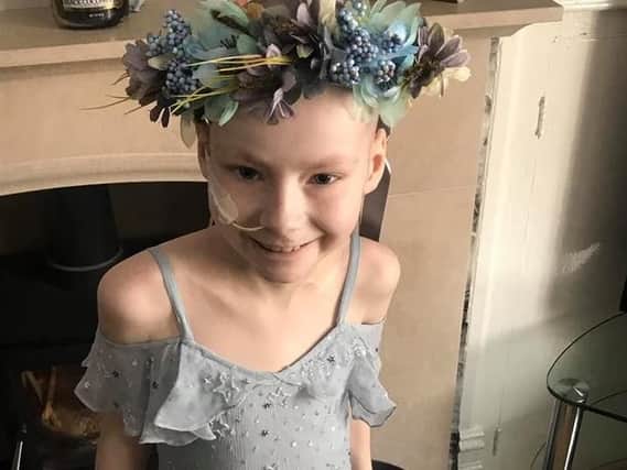 Brave Tia Taggart poses in a dress and garland of flowers sent to her by a well wisher for her 10th birthday.
