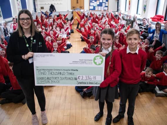 Imogen Osbaldeston with her brother Jude presents the cheque to Lily Preston, community fundraising officer from Royal Manchester Children's Hospital.