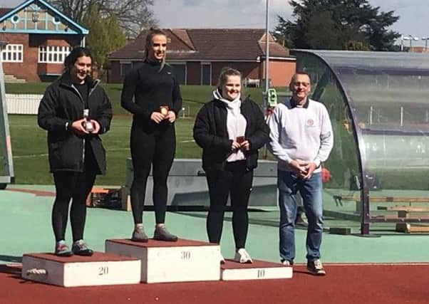 Charlotte Williams on top of the podium with coach Michael Hitchon, father of Olympic bronze medalist Sophie Hitchon