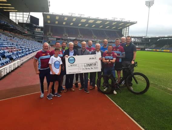 Burnley cyclists hand over cheque to Barry Kilby following their sponsored bike ride