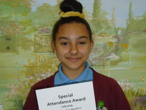 A proud Zahra shows off the award she received for attaining seven years of 100 per cent attendance at her school.