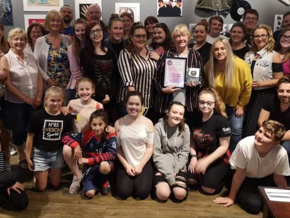 Hazel Hodder, honorary president of Burnley Panto Society, holding the Most Accomplished Panto, alongside cast and crew.