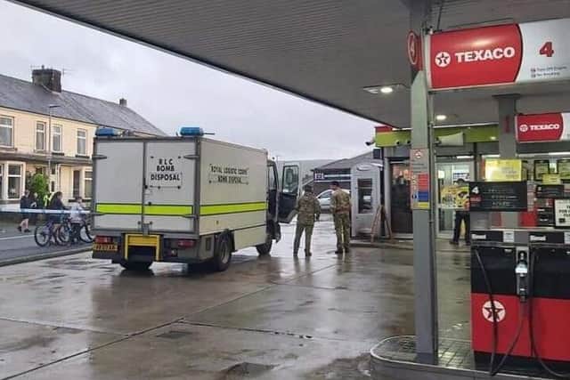 Bomb disposal officers at the scene of the garage where the device was found attached to the cash machine this afternoon.