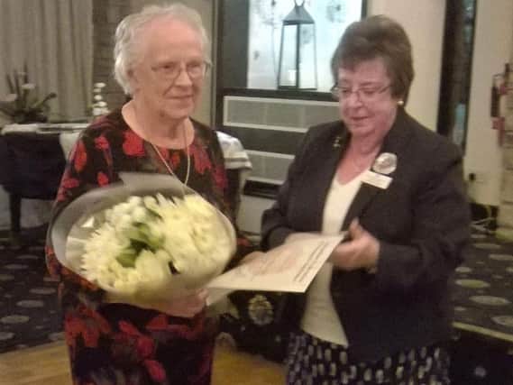 Nora Ashcroft receiving 60 years long service award and flowers from NFWI Chairman Jackie Hobson