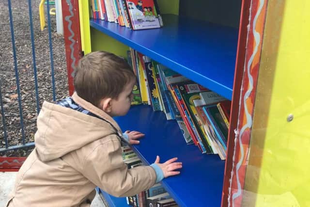 Little Myles Caldecott (two) checks out the selection of books at the new and improved Ightenhill little free library.