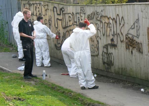 Youngsters  cleaning a fence they spraypainted as part of restorative justice measures