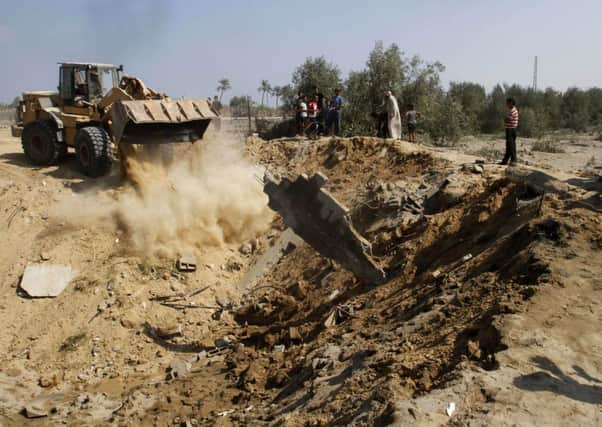 Palestinians watch a bulldozer filling a crater caused by an Israeli airstrike in the Nusseirat refugee camp, central Gaza Strip. (AP Photo/Hatem Moussa)
