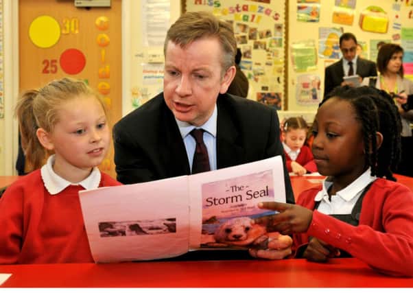 Education Secretary Michael Gove reads for Lia Thomas (left) and Chloe Teggart at the Cuckoo Hall Primary School in Edmonton, north east London. Photo: John Stillwell/PA Wire