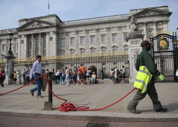 A man puts out a rope barrier outside Buckingham Palace in central London, as the Duchess of Cambridge was admitted to hospital in the early stages of labour this morning. Photo: Anthony Devlin/PA Wire