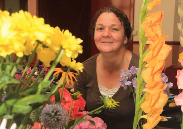 Dianne Mason takes a closer look at the flowers on display at the Reedley Hallows flowers show.