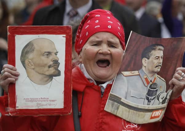 A woman shouts as she carries portraits of Soviet founder Vladimir Lenin, left, and Soviet dictator Josef Stalin, right, during a Communist Party supporters rally to mark May Day in Moscow (AP Photo/Mikhail Metzel)