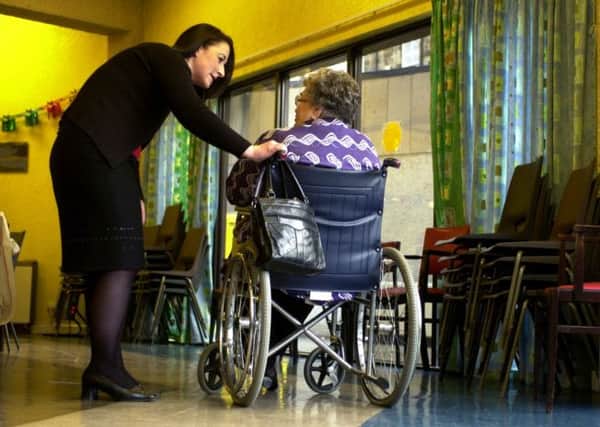 Nurse in a care home talking to an elderly woman in a wheelchair