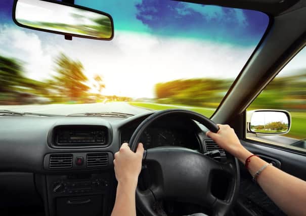 Hands on steering wheel of a car and blurred asphalt road