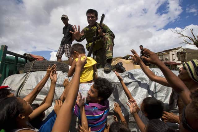 Typhoon Haiyan survivors crowd around a Phillippine soldier to ask for food as aid arrives in the village of Marabut. (AP Photo/David Guttenfelder)
