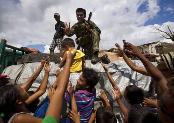 Typhoon Haiyan survivors crowd around a Phillippine soldier to ask for food as aid arrives in the village of Marabut. (AP Photo/David Guttenfelder)
