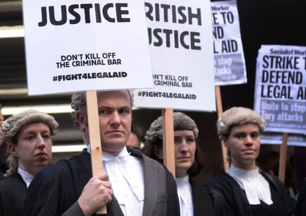 Barristers and solicitors outside Southwark Crown Court, London, during a nationwide strike against Government plans to cut fees as part of a bid to slash £220 million from the  legal aid budget by 2018/19. PRESS ASSOCIATION Photo. Picture date: Monday January 6, 2014. Barristers have chosen not to attend proceedings at courts in cities including London, Manchester, Liverpool, Leeds, Birmingham, Newcastle, Winchester, Bristol and Cardiff. Criminal Bar Association chair Nigel Lithman said the "strike" had the backing of almost every chambers and accused Justice Secretary Chris Grayling of "manipulating" official figures to falsely portray lawyers doing criminal aid work as high-earning "fat cats". See PA story POLITICS LegalAid. Photo credit should read: Stefan Rousseau/PA Wire