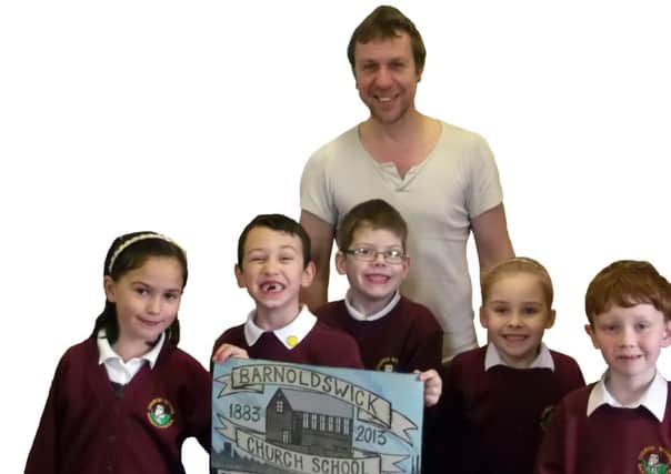 Ex-Terrorvision frontman Tony Wright, who now runs Oldfield Press, with pupils, a poster and printing equipment at Barnoldswick CE Primary School.