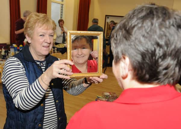 Janet Stanford holds the mirror for Caroline Athay to check to see what the earings look like.