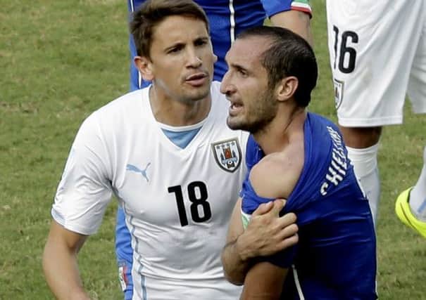 Biting point: Italys Giorgio Chiellini, right, shows his shoulder after colliding with Uruguays Luis Suarezs mouth as Uruguays Gaston Ramirez watches during the group D match between Italy and Uruguay