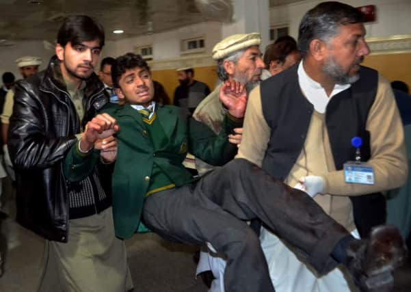 Pakistani volunteers carry a student injured in the shootout at a school under attack by Taliban gunmen, at a local hospital in Peshawar, Pakistan (AP Photo/Mohammad Sajjad)