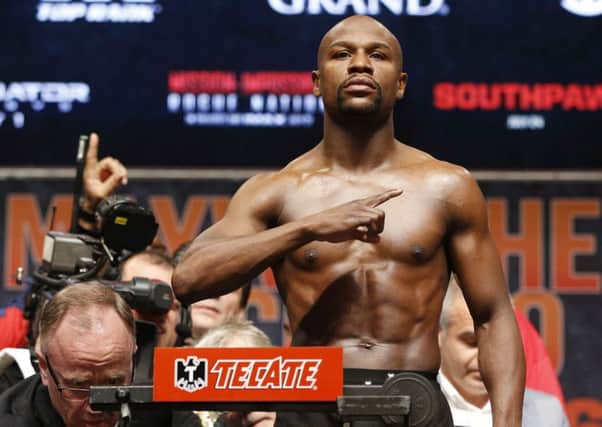 Floyd Mayweather Jr. poses during his weigh-in on Friday, May 1, 2015 in Las Vegas. The world weltherweight title fight between Mayweather Jr. and Manny Pacquiao is scheduled for May 2. At lower left is Nevada State Athletic Commission Executive Director Robert Bennett. (AP Photo/John Locher)