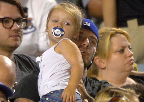 Retired soccer player David Beckham holds his daughter Harper as they watch the Los Angeles Dodgers a couple of years ago.  (AP Photo/Mark J. Terrill)