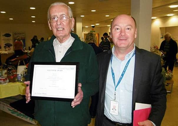 VOLUNTEERING STALWART: John White receives his special 50 Year Volunteering certificate and gift from Kevin Moynes, director of human resources (s)